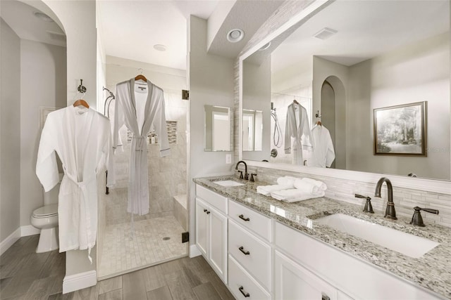 bathroom with vanity, tasteful backsplash, hardwood / wood-style flooring, walk in shower, and toilet