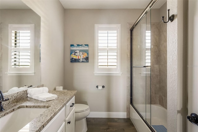 full bathroom with hardwood / wood-style floors, vanity, toilet, and enclosed tub / shower combo