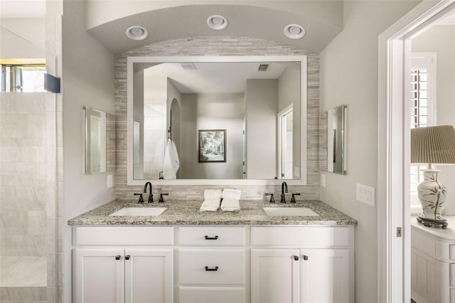 bathroom with a shower, vaulted ceiling, vanity, and a healthy amount of sunlight