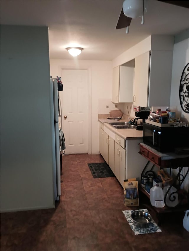 kitchen with stainless steel fridge, white cabinets, and sink