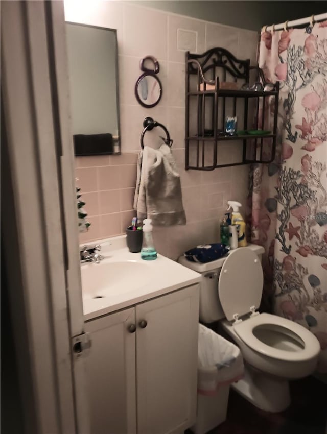 bathroom featuring toilet, vanity, tile walls, and backsplash