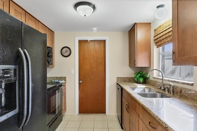 kitchen with light tile patterned flooring, black appliances, sink, and light stone counters