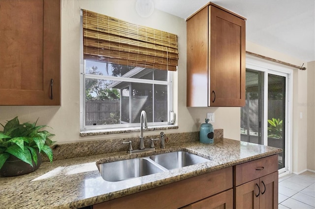 kitchen featuring light tile patterned flooring, sink, and light stone counters