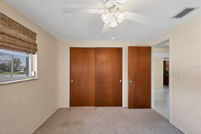 unfurnished bedroom featuring a ceiling fan, multiple closets, visible vents, and carpet