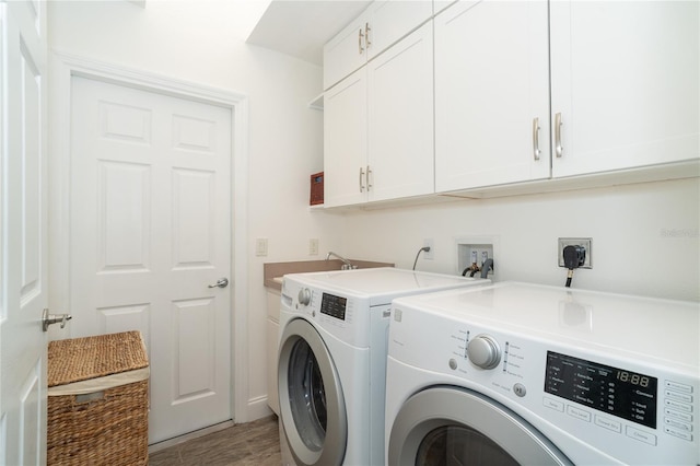 laundry area with light hardwood / wood-style flooring, washer and dryer, and cabinets