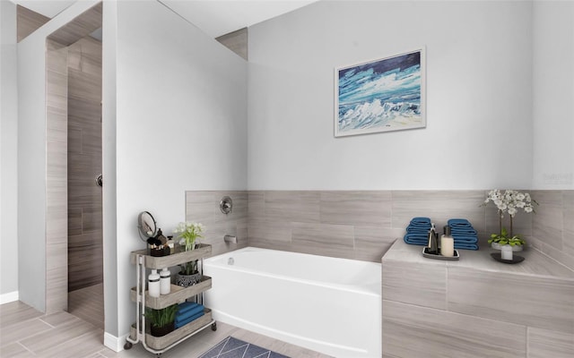 full bathroom with a garden tub and baseboards