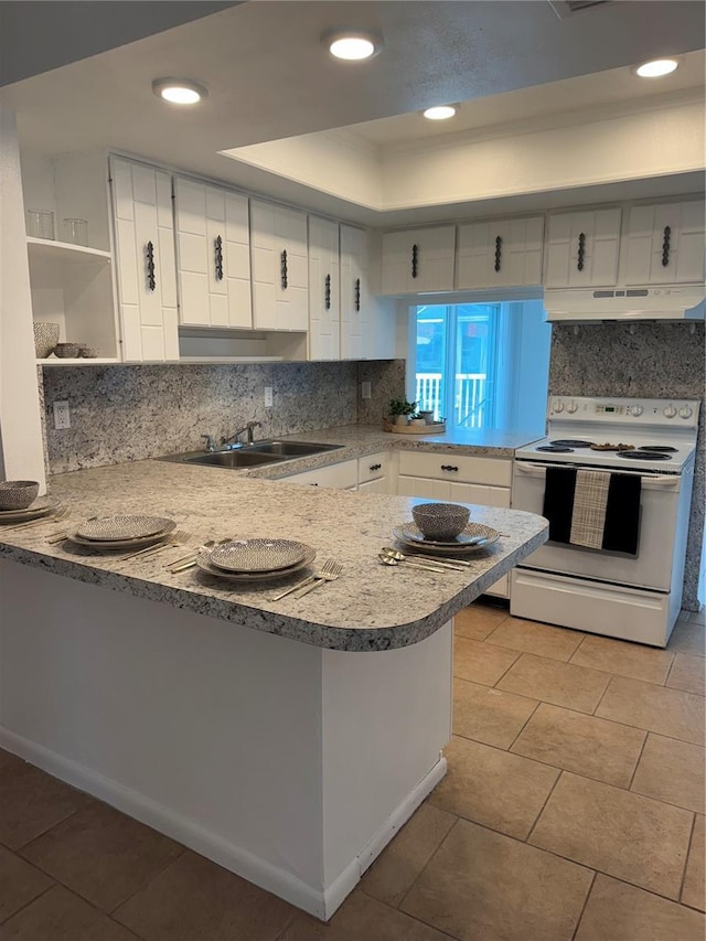 kitchen with kitchen peninsula, white cabinetry, backsplash, a tray ceiling, and electric stove