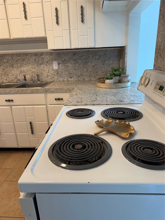 kitchen featuring sink, white cabinetry, light tile patterned floors, electric range, and backsplash