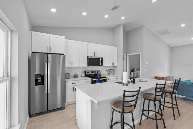 220 Mark Twain Ln, Rotonda West, FL 33947 - kitchen featuring visible vents, a kitchen island with sink, a sink, appliances with stainless steel finishes, and vaulted ceiling