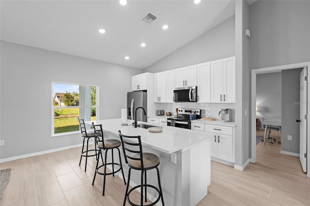 220 Mark Twain Ln, Rotonda West, FL 33947 - kitchen featuring visible vents, a kitchen island with sink, a breakfast bar area, white cabinets, and stainless steel appliances