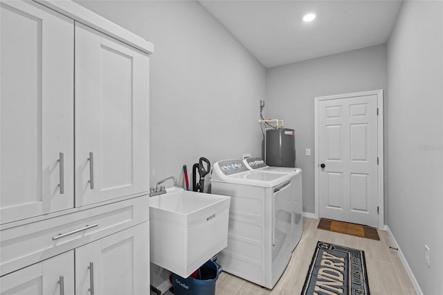 220 Mark Twain Ln, Rotonda West, FL 33947 - laundry area featuring light wood finished floors, washer and dryer, a sink, cabinet space, and water heater