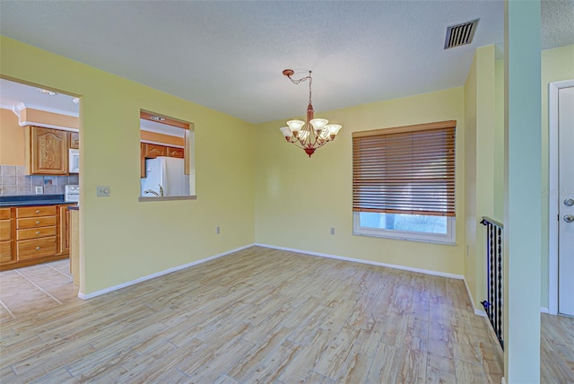 612 Deerwood Ave Unit 169, Englewood, FL 34223 - spare room with light wood-style floors, a chandelier, baseboards, and a textured ceiling