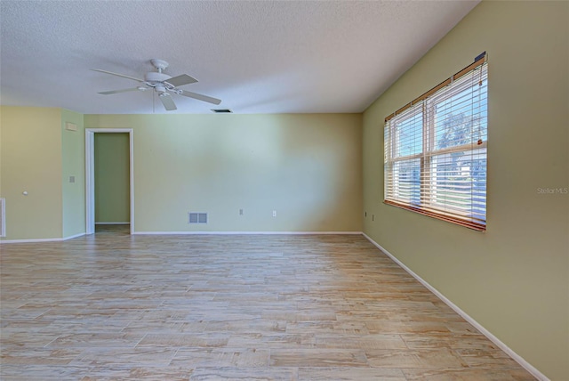 spare room with a textured ceiling, light wood-type flooring, and ceiling fan