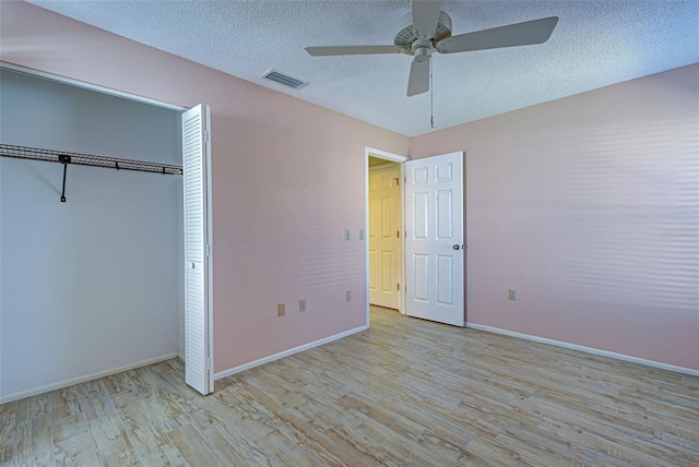 unfurnished bedroom with light hardwood / wood-style floors, a closet, a textured ceiling, and ceiling fan