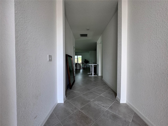 hallway with dark tile patterned floors and a textured ceiling