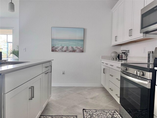 kitchen featuring hanging light fixtures, stainless steel appliances, sink, light tile patterned floors, and white cabinets