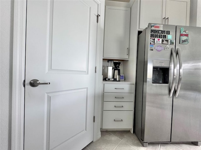 kitchen with stainless steel fridge with ice dispenser, white cabinets, and light tile patterned floors