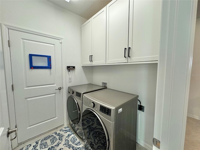 laundry area with washer and dryer, a textured ceiling, and cabinets