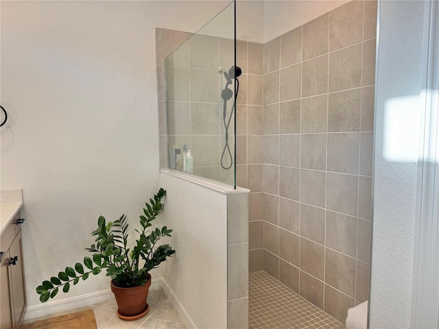 bathroom with vanity, a tile shower, and tile patterned flooring