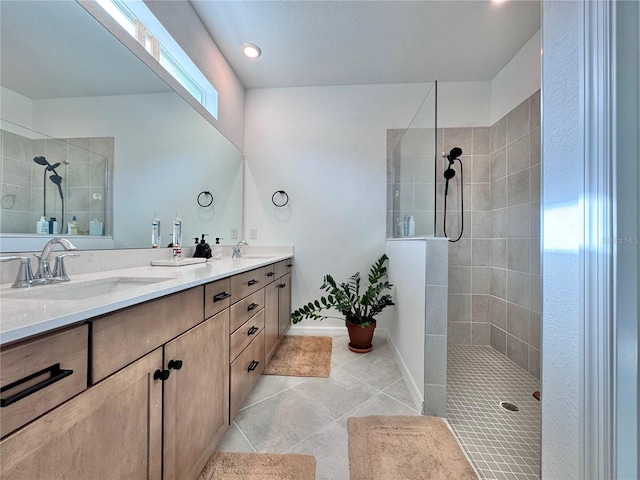 bathroom with vanity, a tile shower, and tile patterned floors