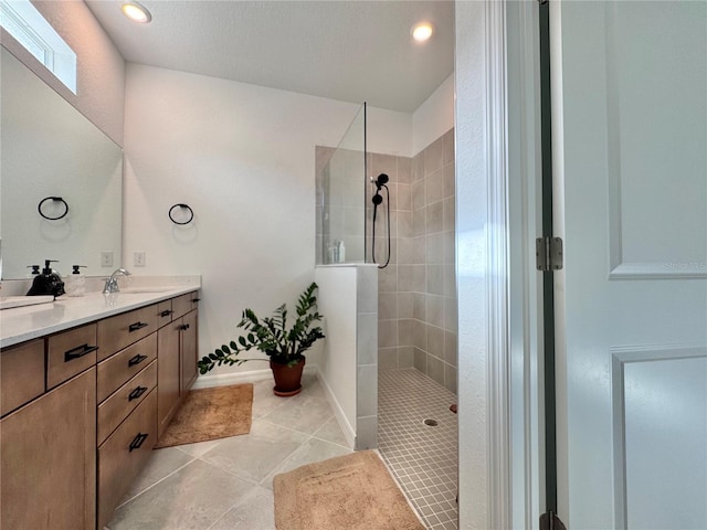 bathroom featuring vanity, a textured ceiling, a tile shower, and tile patterned floors