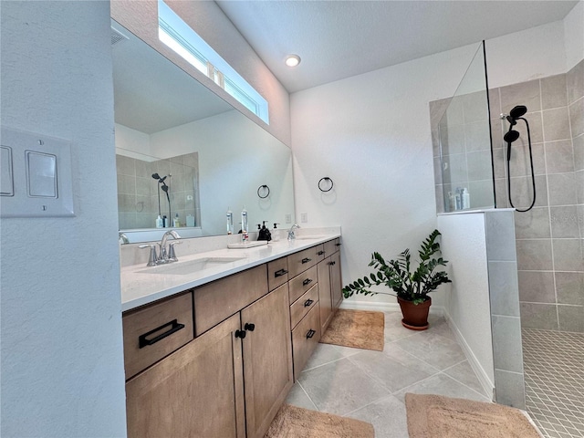 bathroom featuring a tile shower, vanity, and tile patterned flooring