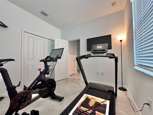 workout area featuring light tile patterned flooring and a textured ceiling