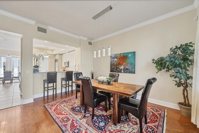 dining area featuring ceiling fan, ornamental molding, and dark hardwood / wood-style flooring