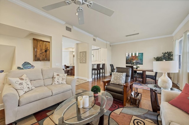 living room with ornamental molding, ceiling fan, and light hardwood / wood-style floors