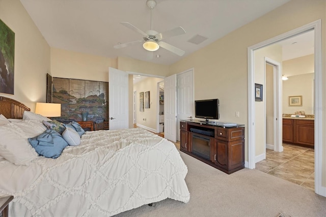 bedroom with ceiling fan, ensuite bath, and light carpet