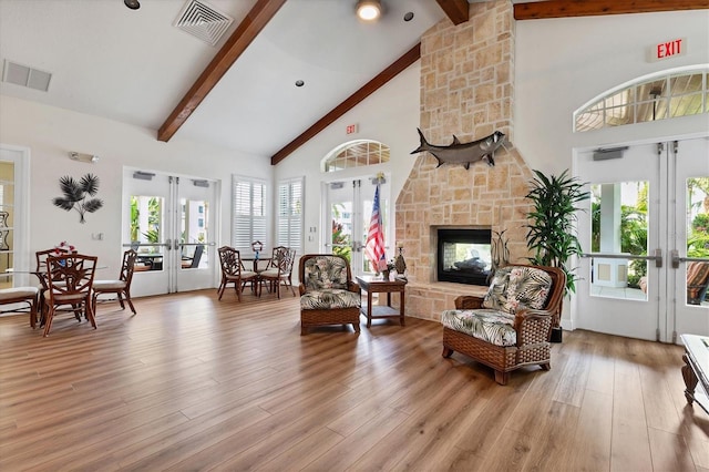 living room featuring beamed ceiling, high vaulted ceiling, light wood-type flooring, and french doors