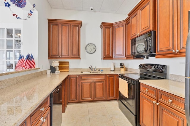 kitchen with sink, light tile patterned floors, light stone counters, black appliances, and a drop ceiling