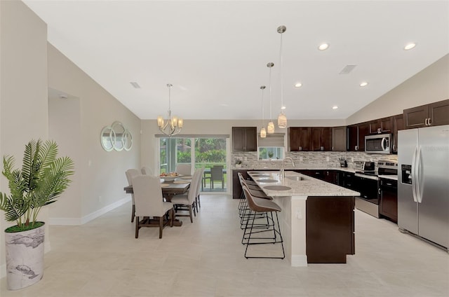 2775 Wyola Ave, North Port, FL 34286 - kitchen with lofted ceiling, decorative backsplash, stainless steel appliances, dark brown cabinetry, and an inviting chandelier