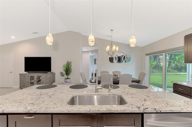 kitchen with lofted ceiling, light stone countertops, sink, and an island with sink