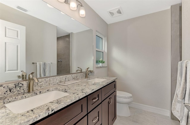 bathroom with vanity, toilet, tile patterned floors, and tiled shower