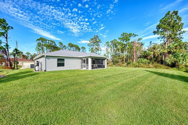 rear view of house featuring a sunroom and a lawn