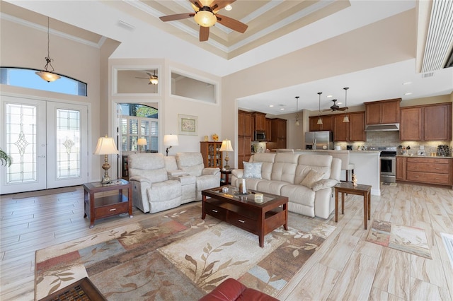 living room with light hardwood / wood-style floors, crown molding, a high ceiling, and ceiling fan