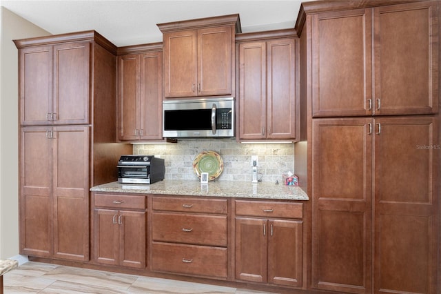 kitchen with light stone countertops, backsplash, and light hardwood / wood-style floors