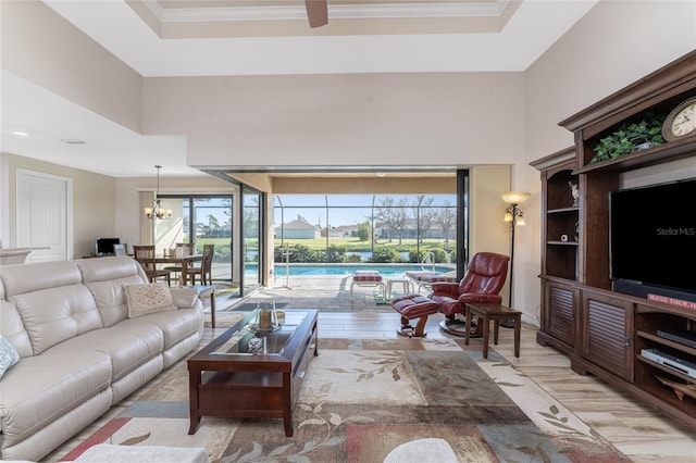 living room featuring light hardwood / wood-style floors, an inviting chandelier, a healthy amount of sunlight, and crown molding