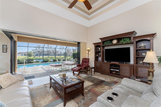 living room with crown molding, hardwood / wood-style flooring, a high ceiling, and ceiling fan