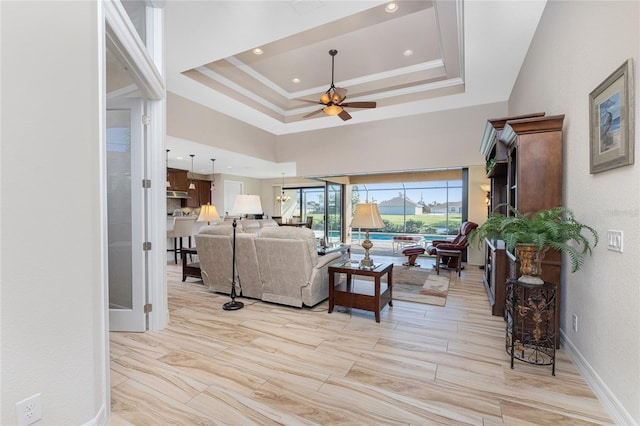 living room with ornamental molding, a raised ceiling, and ceiling fan