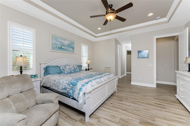 bedroom with a tray ceiling, multiple windows, light wood-type flooring, and ceiling fan