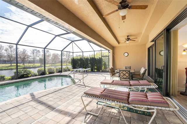 view of swimming pool with a patio area, glass enclosure, a water view, and ceiling fan