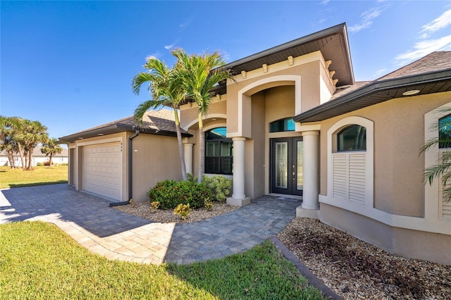 view of front of property featuring stucco siding, driveway, a garage, and french doors