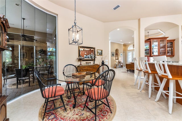 dining space with light tile patterned flooring, an inviting chandelier, and crown molding