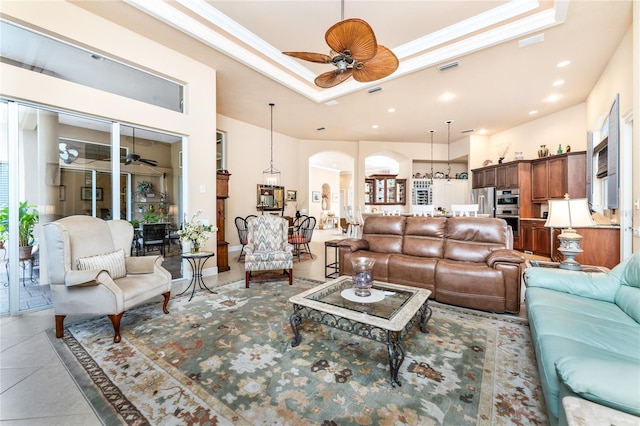 tiled living room with crown molding, ceiling fan, and a raised ceiling