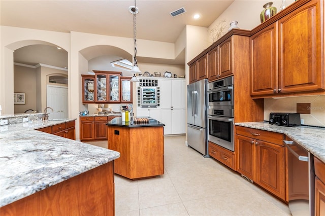 kitchen with pendant lighting, stainless steel appliances, light stone counters, and a center island