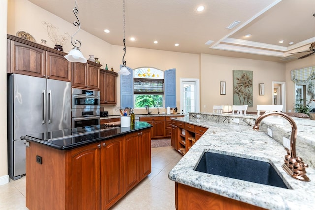 kitchen featuring stainless steel appliances, dark stone counters, sink, ornamental molding, and a spacious island