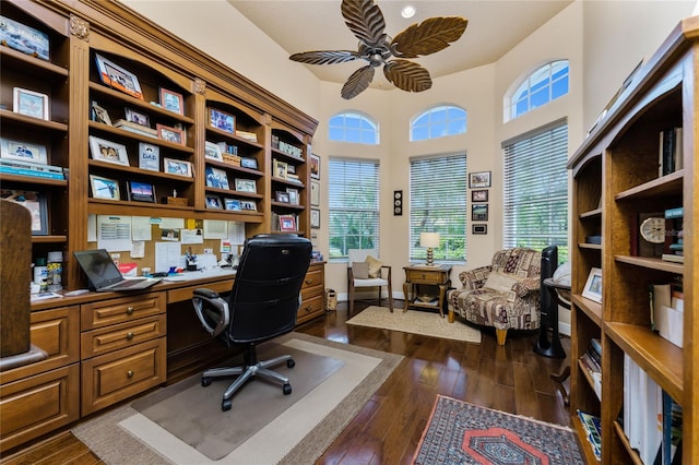 home office featuring a wealth of natural light, ceiling fan, built in desk, and dark hardwood / wood-style flooring