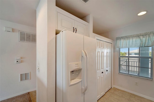 kitchen featuring white cabinetry, white fridge with ice dispenser, and light tile patterned floors